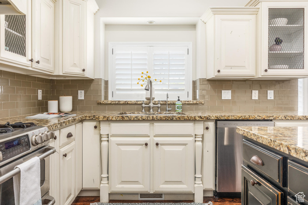 Kitchen with appliances with stainless steel finishes, light stone countertops, and white cabinetry