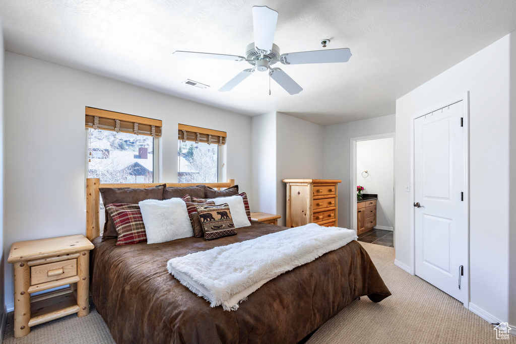 Bedroom featuring ceiling fan, light carpet, and connected bathroom