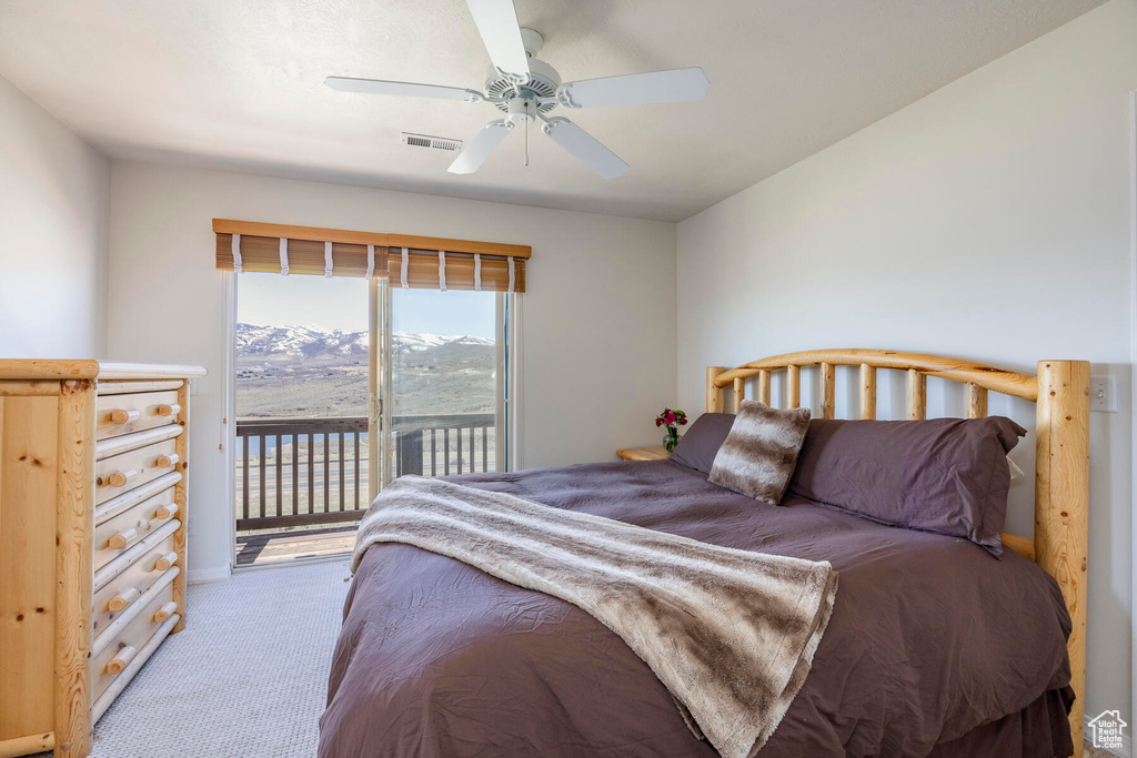 Bedroom with light colored carpet, ceiling fan, a mountain view, and access to exterior