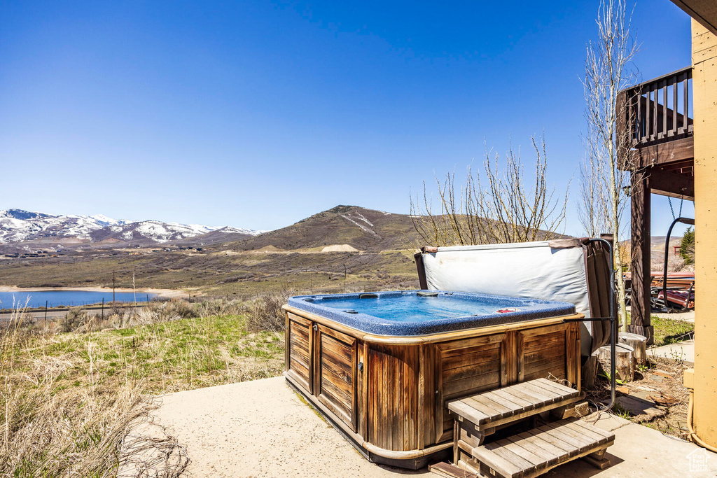 View of terrace featuring a hot tub and a water and mountain view