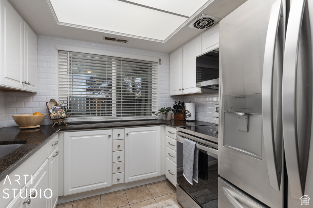 Kitchen featuring white cabinets, backsplash, and stainless steel appliances