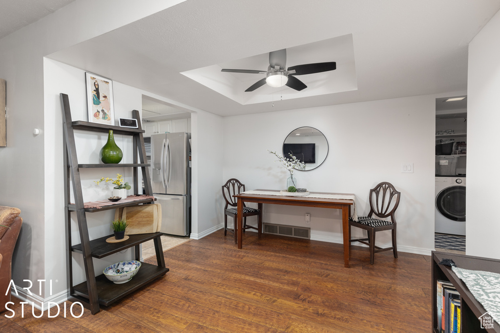 Miscellaneous room with washer / dryer, ceiling fan, dark hardwood / wood-style floors, and a tray ceiling