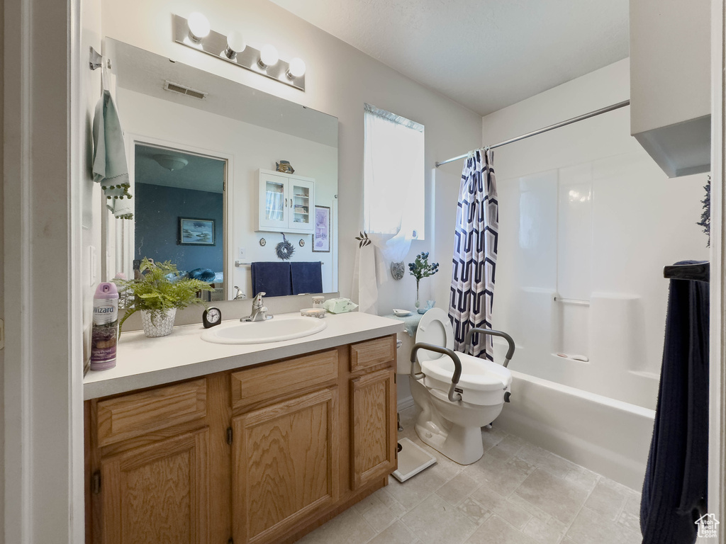 Full bathroom featuring shower / tub combo with curtain, vanity, toilet, and tile flooring