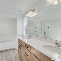 Bathroom featuring double vanity, wood-type flooring, and plus walk in shower