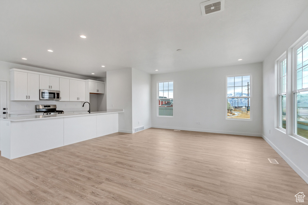 Kitchen with a healthy amount of sunlight, light hardwood / wood-style floors, and stove
