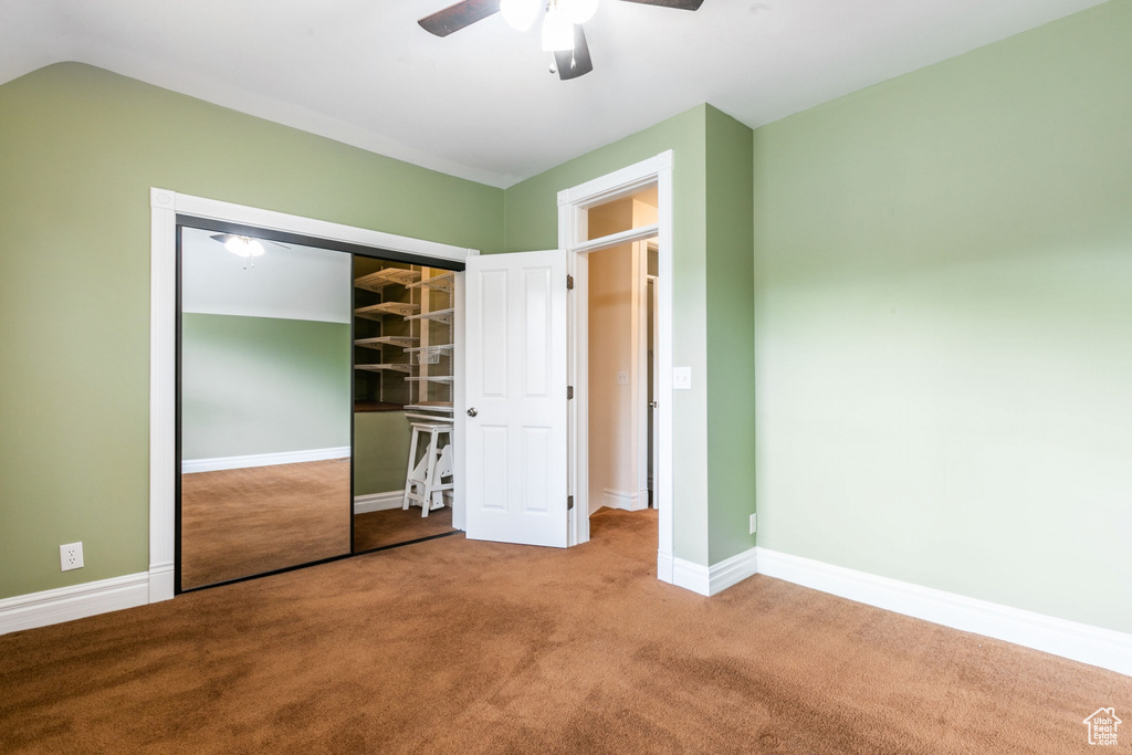 Unfurnished bedroom with light colored carpet, a closet, ceiling fan, and lofted ceiling