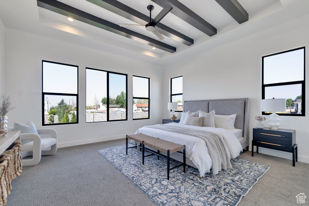 Carpeted bedroom with beamed ceiling, a raised ceiling, and ceiling fan