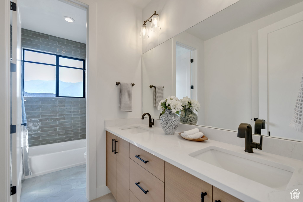 Full bathroom featuring tile patterned flooring, toilet, double sink vanity, and tiled shower / bath combo