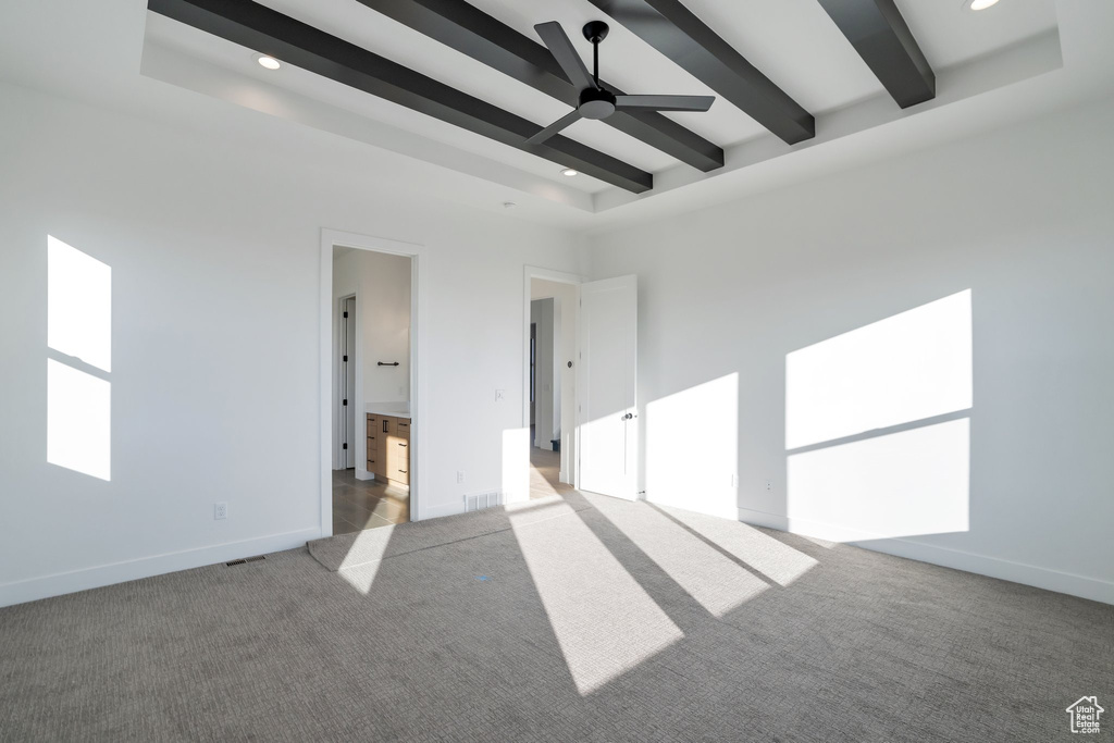Carpeted empty room with beamed ceiling and ceiling fan