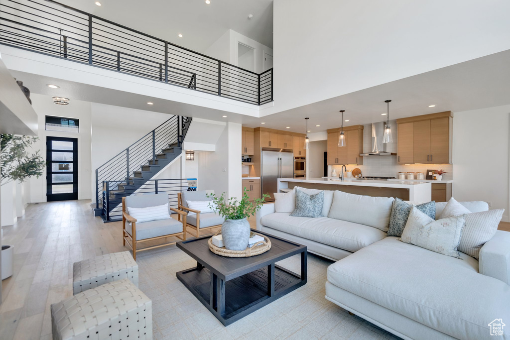 Living room featuring sink, light hardwood / wood-style floors, and a towering ceiling