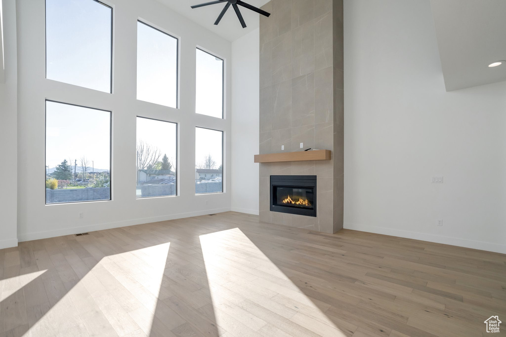 Unfurnished living room featuring light hardwood / wood-style floors, tile walls, and a tiled fireplace