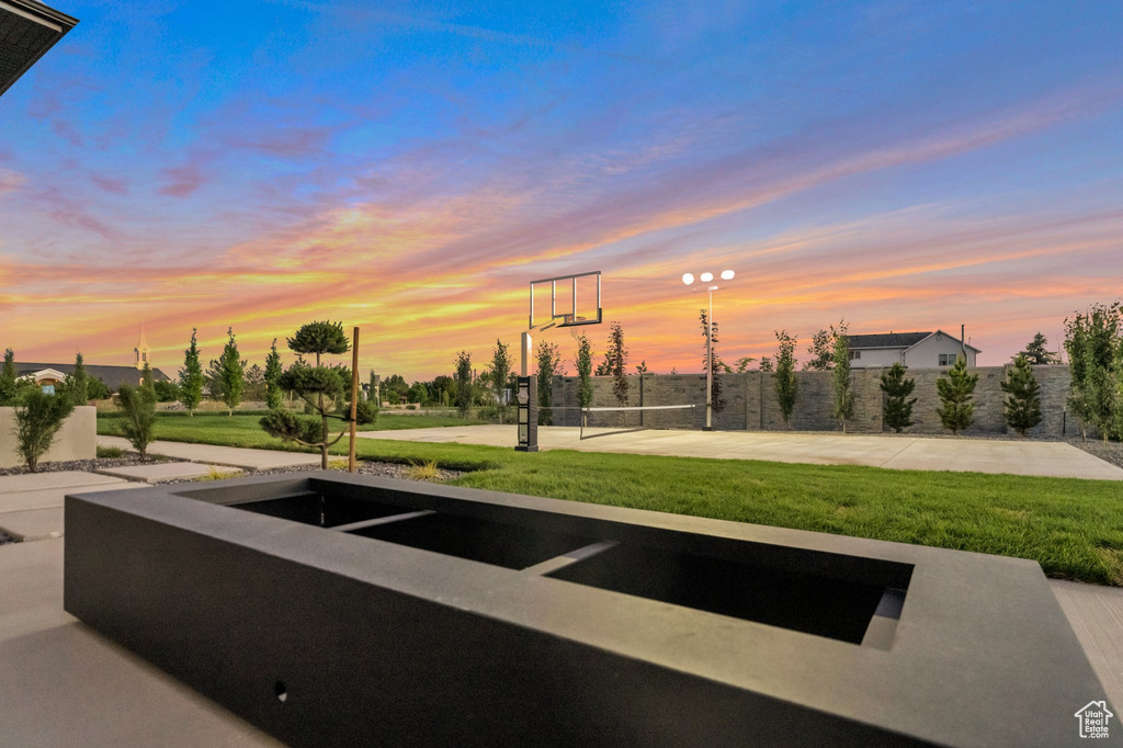 Exterior space with basketball hoop and a lawn