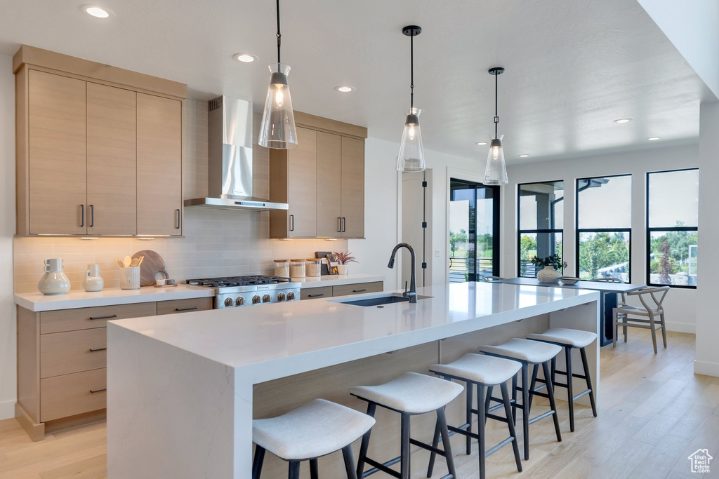 Kitchen featuring light hardwood / wood-style floors, light brown cabinetry, and wall chimney range hood