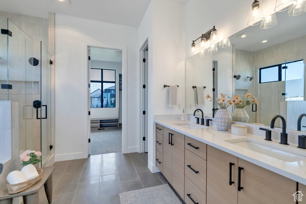 Bathroom featuring a shower with door, tile patterned floors, and double sink vanity