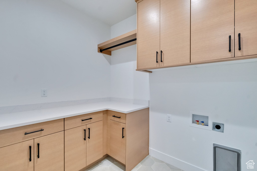 Laundry area featuring hookup for an electric dryer, cabinets, hookup for a washing machine, and light tile patterned floors