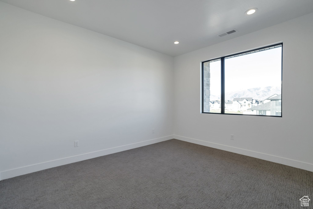 Spare room featuring dark colored carpet