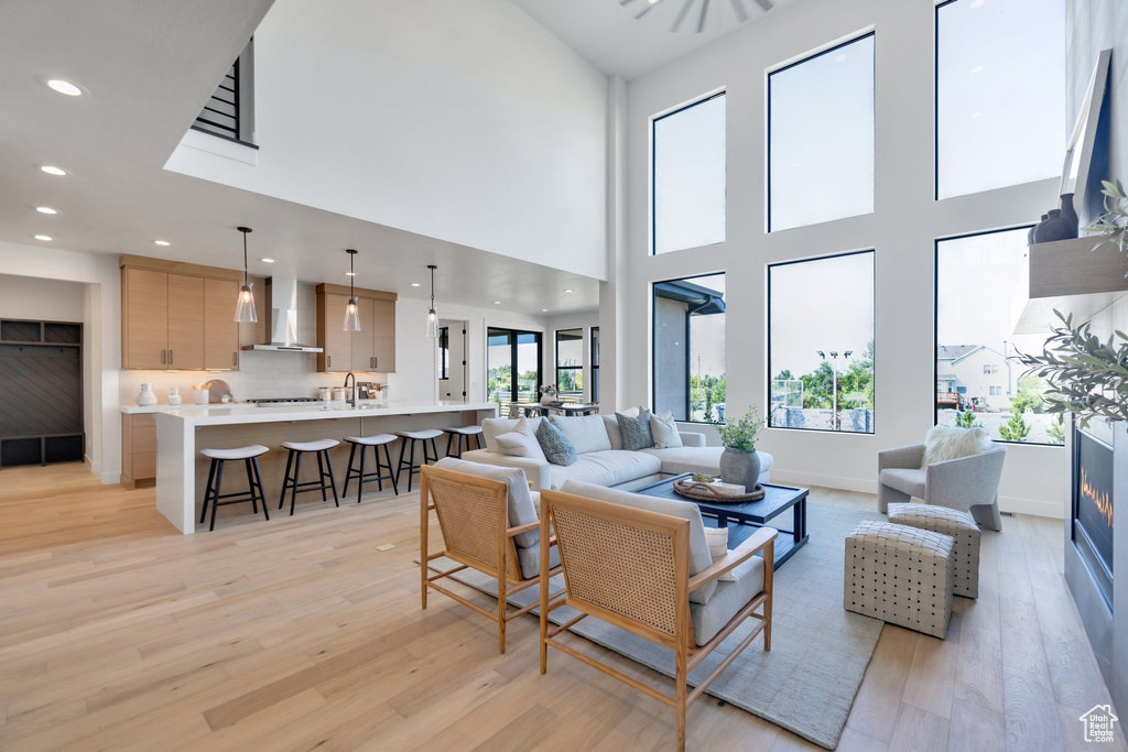 Living room featuring light hardwood / wood-style floors, sink, and a high ceiling