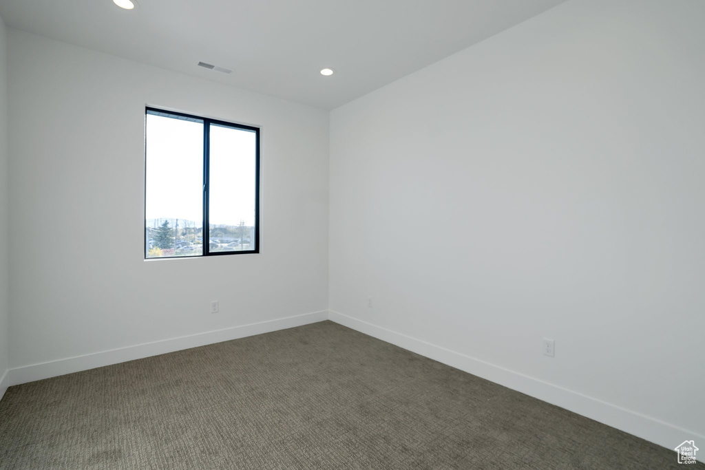 Unfurnished room featuring dark colored carpet