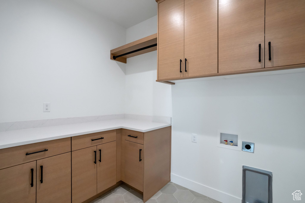 Washroom with hookup for a washing machine, electric dryer hookup, cabinets, and light tile flooring