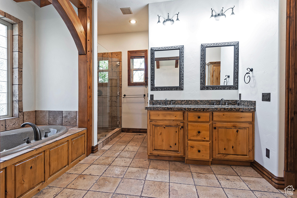 Bathroom featuring shower with separate bathtub, dual vanity, and tile flooring
