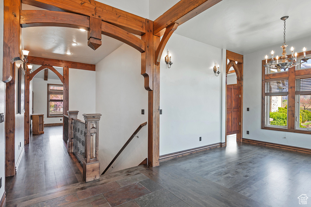 Foyer featuring dark hardwood / wood-style flooring, lofted ceiling with beams, and a chandelier
