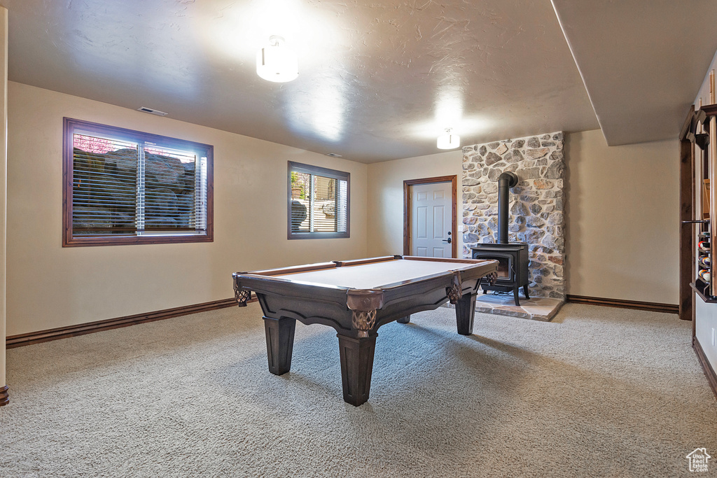 Rec room featuring light colored carpet, a wood stove, and pool table