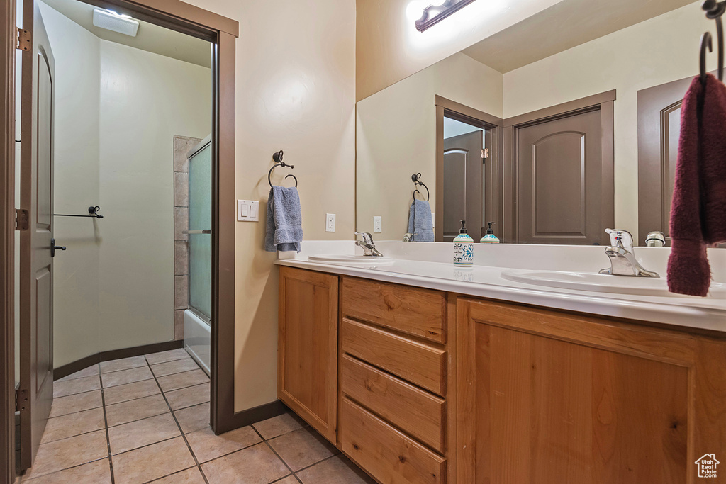 Bathroom featuring shower / bath combination with glass door, dual vanity, and tile flooring