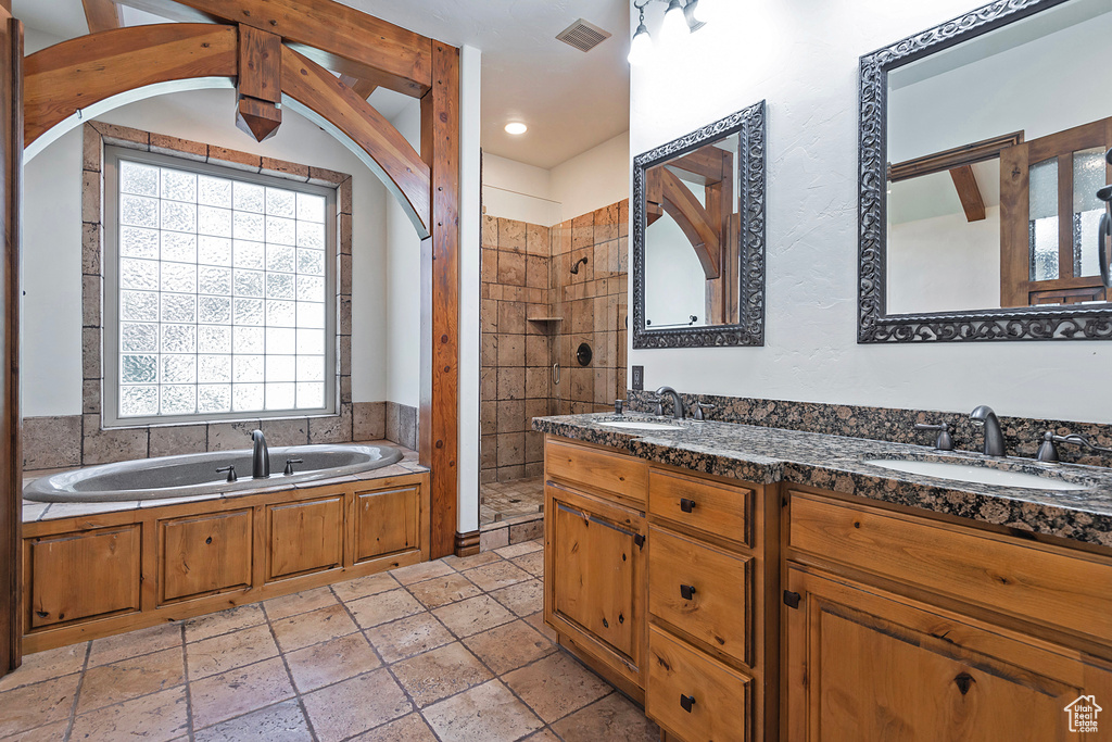 Bathroom featuring tile flooring, separate shower and tub, dual vanity, and a wealth of natural light