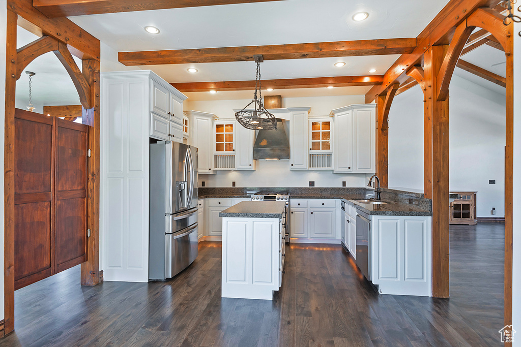 Kitchen featuring premium range hood, decorative light fixtures, dark wood-type flooring, appliances with stainless steel finishes, and a kitchen island
