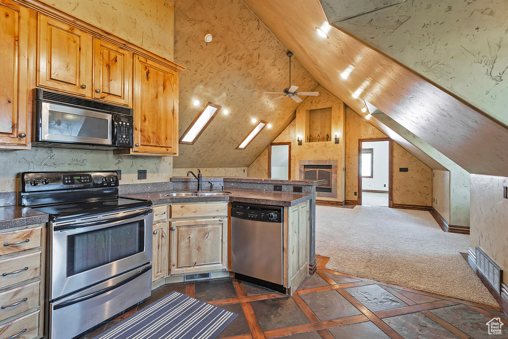 Kitchen featuring dark colored carpet, stainless steel appliances, vaulted ceiling, sink, and ceiling fan
