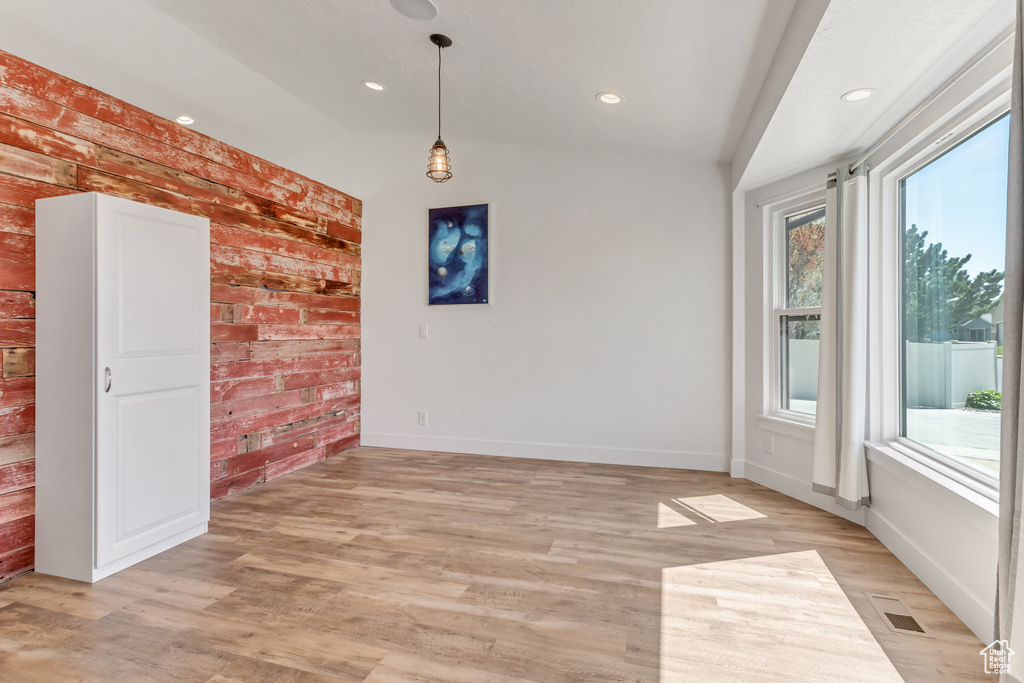 Unfurnished room featuring brick wall and light hardwood / wood-style floors