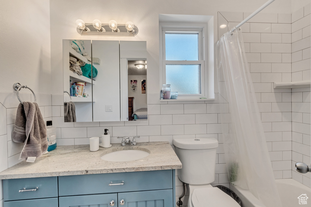 Full bathroom featuring tile walls, tasteful backsplash, vanity, and shower / bath combination with curtain