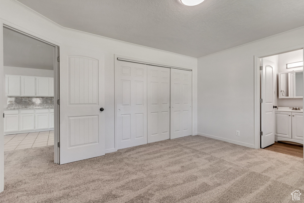 Unfurnished bedroom featuring light colored carpet, sink, and connected bathroom