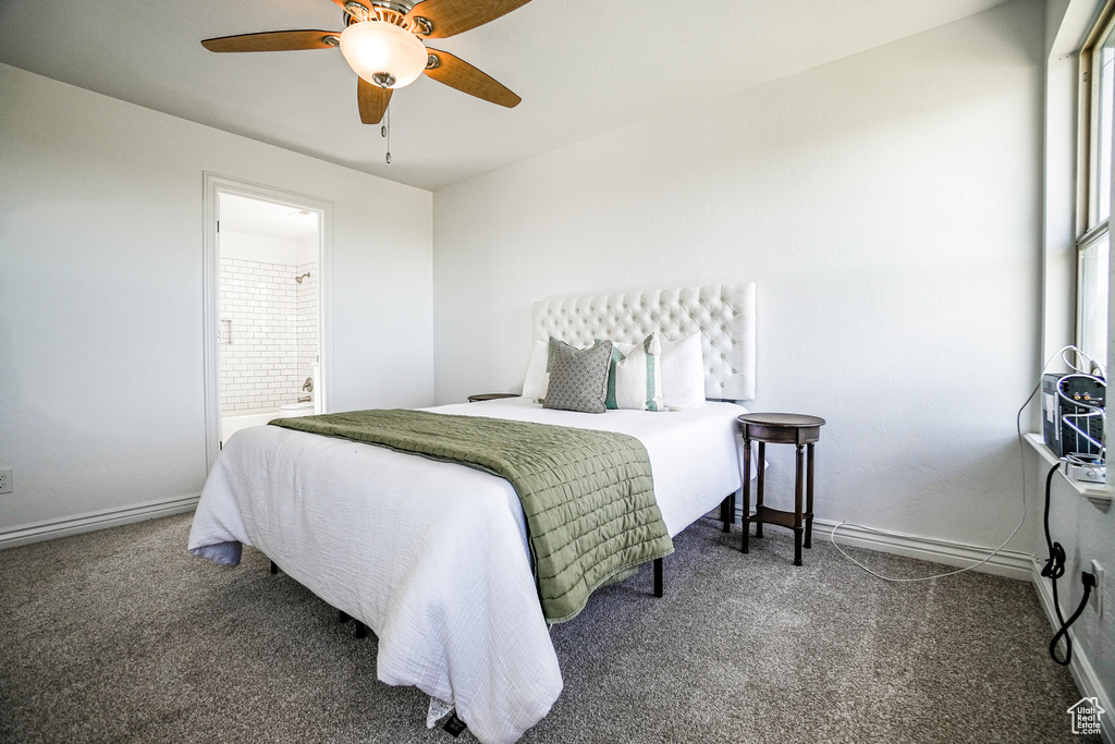 Bedroom featuring ensuite bath, ceiling fan, and dark carpet