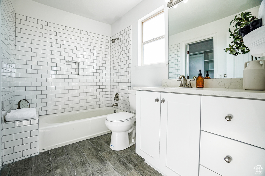 Full bathroom with hardwood / wood-style floors, oversized vanity, tiled shower / bath, and toilet