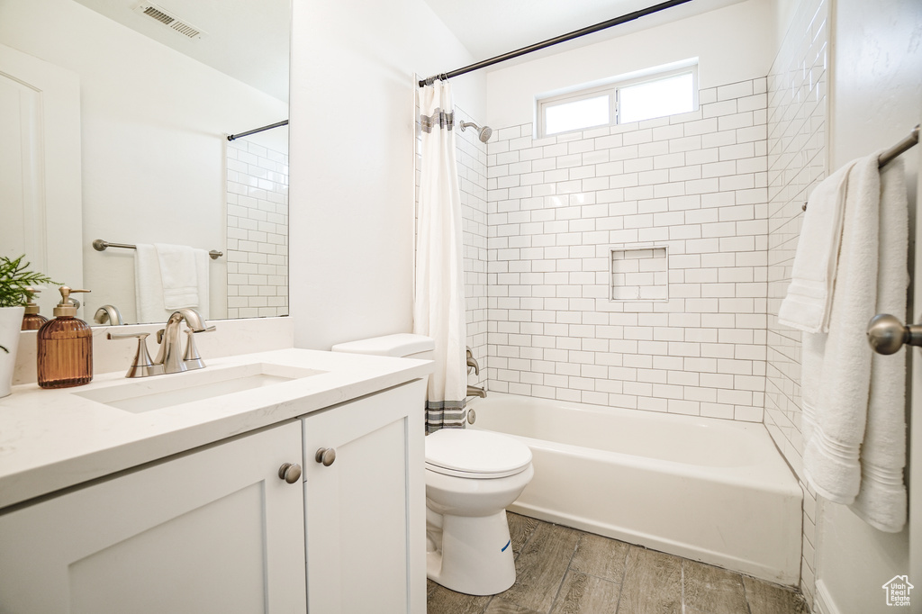 Full bathroom featuring toilet, hardwood / wood-style flooring, large vanity, and shower / bathtub combination with curtain