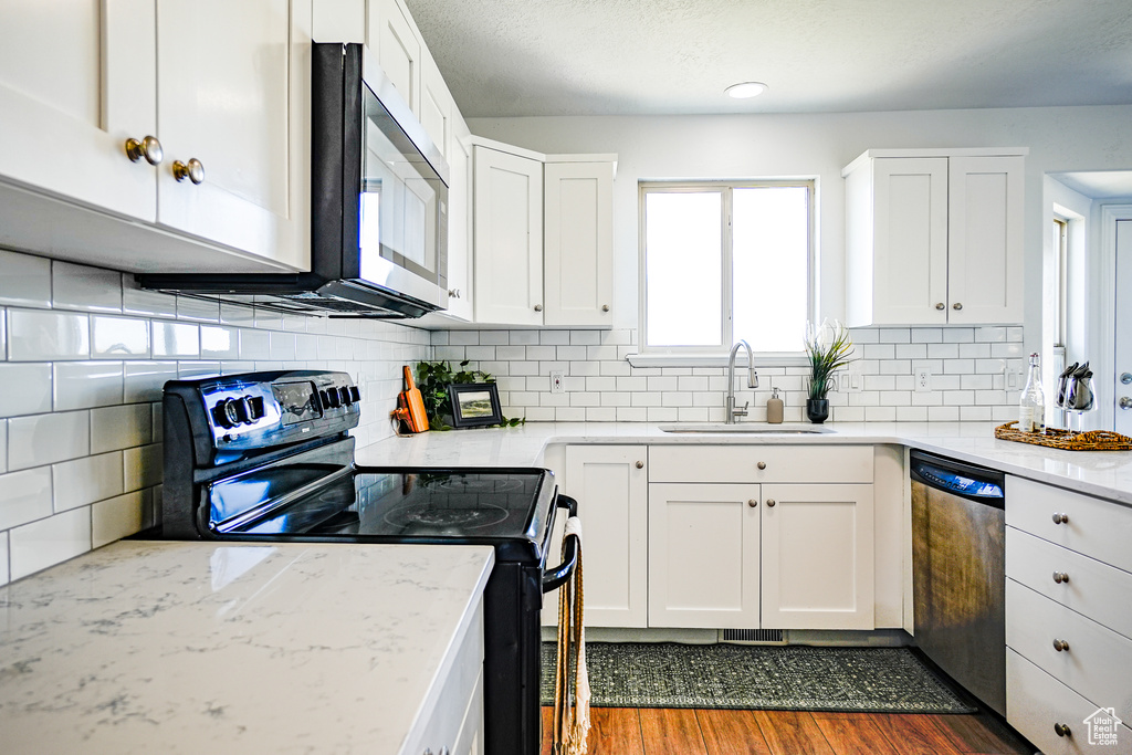 Kitchen featuring white cabinets, dark hardwood / wood-style flooring, appliances with stainless steel finishes, sink, and tasteful backsplash