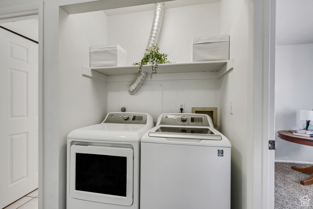 Clothes washing area with light colored carpet and separate washer and dryer