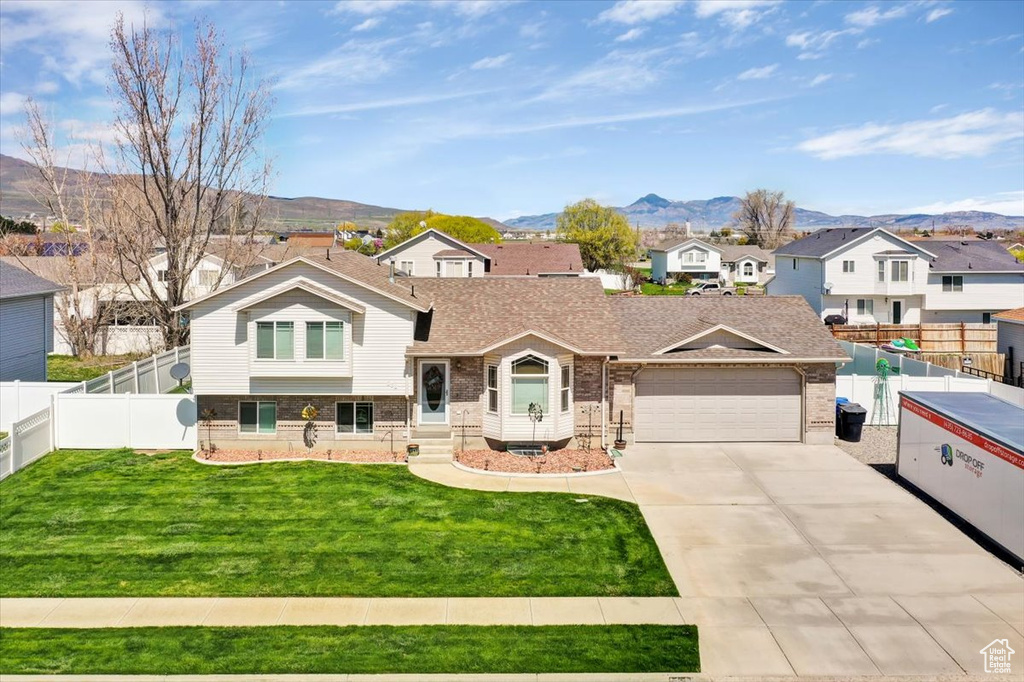 Split level home with a garage, a mountain view, and a front lawn