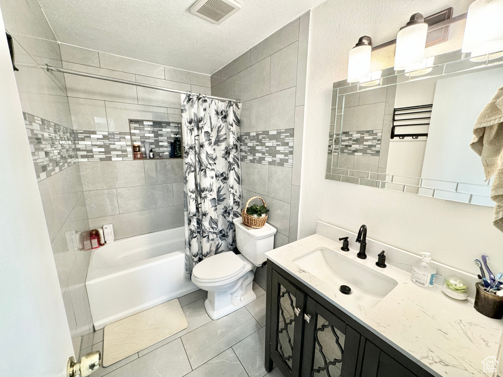 Full bathroom featuring tile floors, tile walls, vanity, shower / tub combo with curtain, and toilet