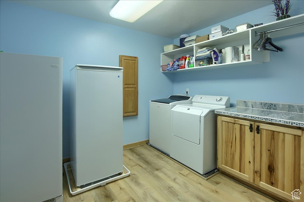 Laundry area with light hardwood / wood-style floors, independent washer and dryer, and cabinets