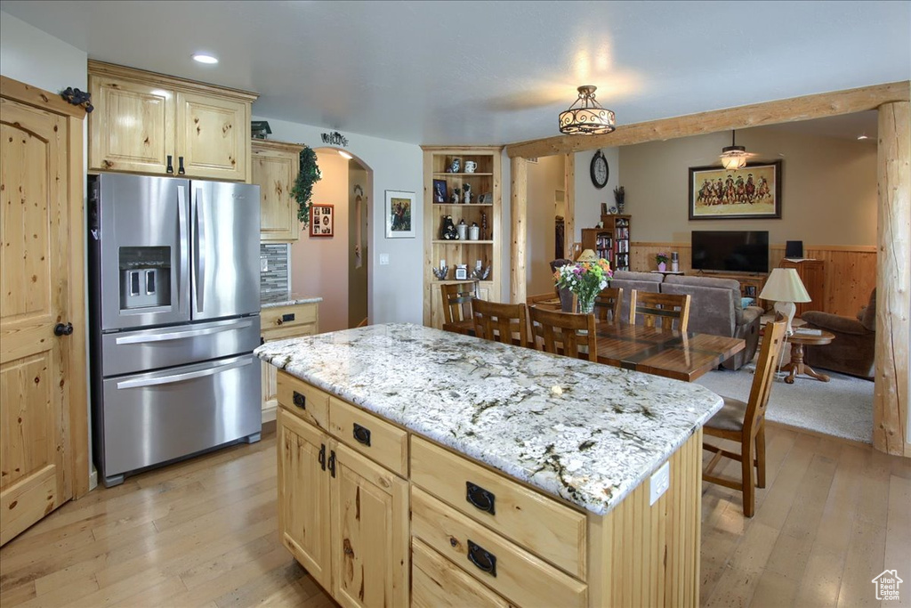 Kitchen with stainless steel fridge with ice dispenser, a kitchen island, light hardwood / wood-style flooring, light stone counters, and light brown cabinetry