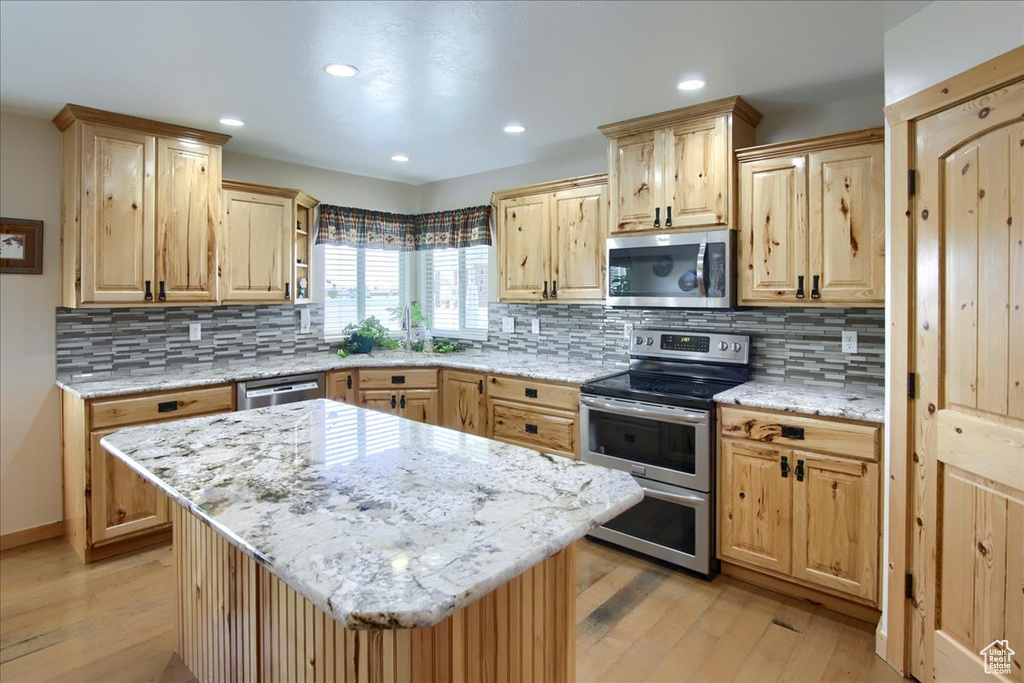 Kitchen featuring light hardwood / wood-style floors, a center island, tasteful backsplash, and stainless steel appliances