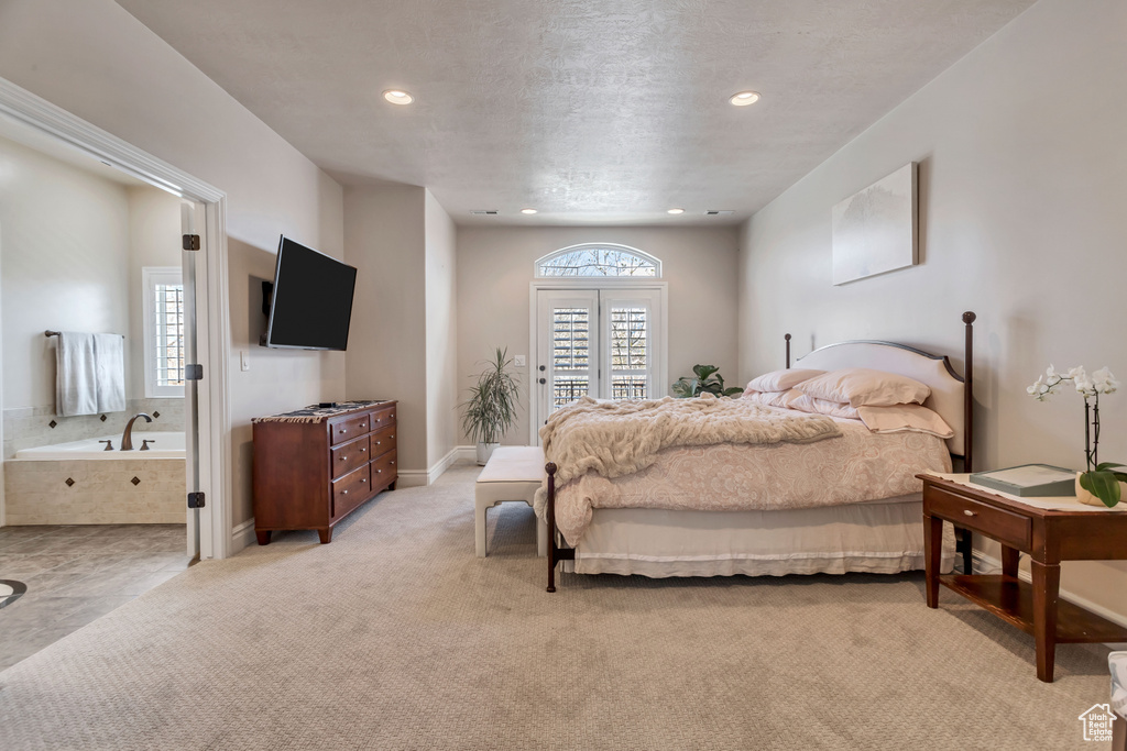 Carpeted bedroom featuring multiple windows and ensuite bathroom