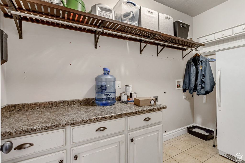 Interior space with washer hookup, hookup for an electric dryer, and light tile floors