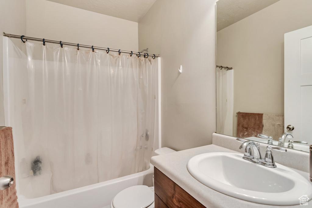 Full bathroom featuring toilet, large vanity, and shower / bathtub combination with curtain