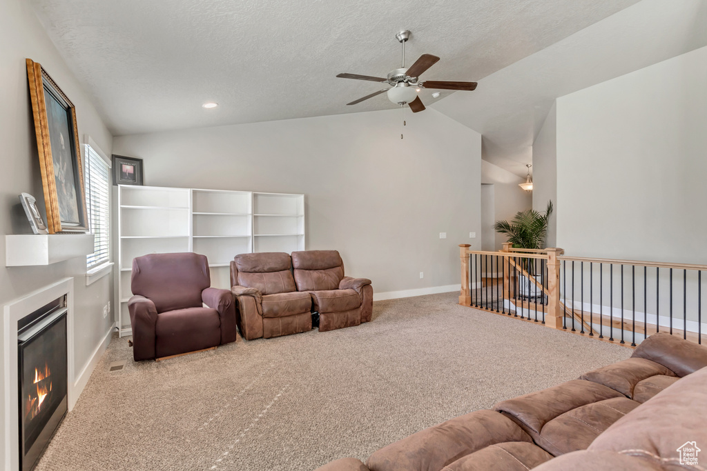 Carpeted living room featuring ceiling fan, a textured ceiling, and lofted ceiling