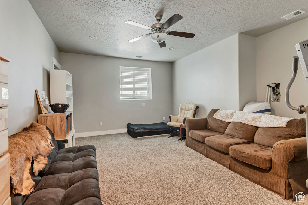 Living room featuring a textured ceiling, ceiling fan, and light carpet