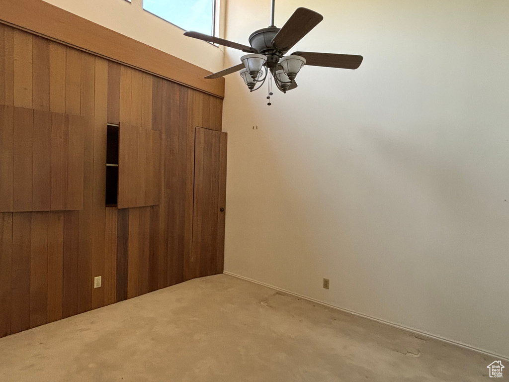 Carpeted empty room with ceiling fan and wooden walls
