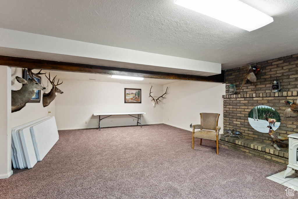 Basement featuring dark colored carpet, brick wall, and a textured ceiling